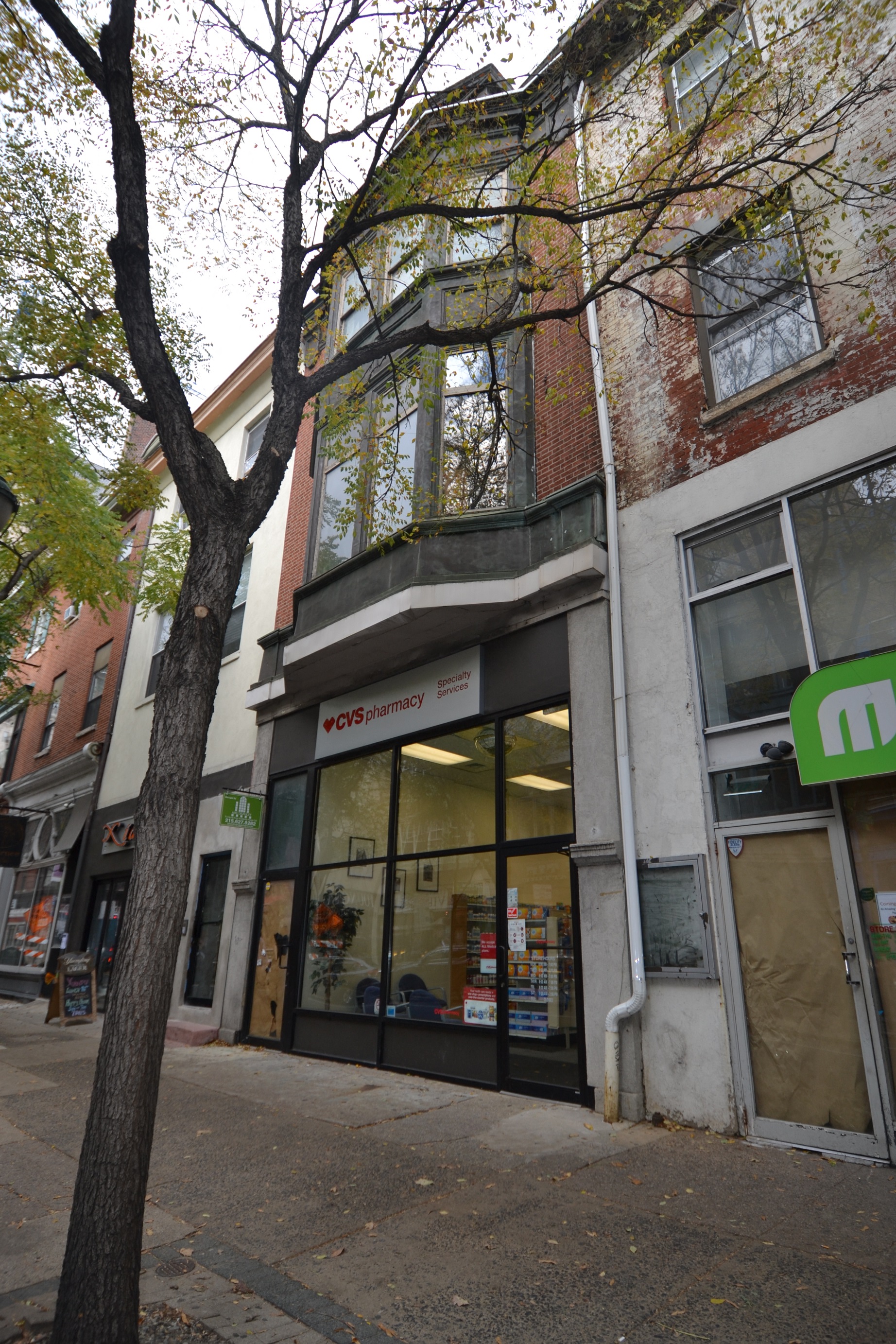 a store front on a city street with a tree